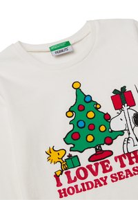 Biała bawełniana koszulka z kolorowym nadrukiem choinki ozdobionej kropkami, postaciami Snoopy'ego i Woodstocka oraz napisem "KOCHAM SEZON ŚWIĄTECZNY".