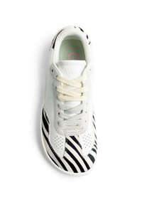 Zapatilla blanca con patrón de rayas de cebra en blanco y negro en la punta y los lados. Cuenta con una lengüeta de tela suave y cordones beige claro.