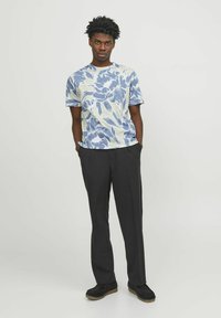 Kortärmad skjorta med ett blått blommönster på en ljus bakgrund, parat med svarta byxor och svarta skor med gummisula.