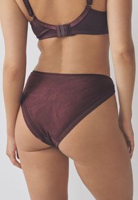 Culotte taille haute bordeaux avec motif texturé, bordure en dentelle festonnée et ceinture élastique, dotée d'une finition lisse et d'un minimum de garnitures.