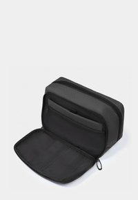 Borsa nera con cerniera realizzata in materiale strutturato con un compartimento frontale aperto e un interno piatto dotato di fascette elastiche per l'organizzazione.