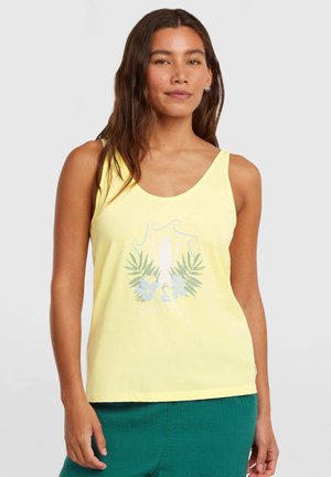 Żółty top na ramiączkach z kwiatowym i deską surfingową nadrukiem, wykonany z miękkiego materiału, z dekoltem w łódkę i luźnym krojem, noszony razem z zielonymi szortami.
