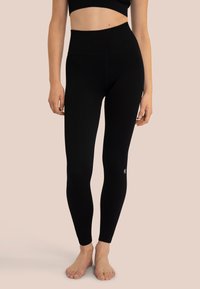 Leggings nere a coste con vita alta, tessuto testurizzato e un piccolo logo sulla parte inferiore della gamba. Design morbido e aderente per il massimo comfort.