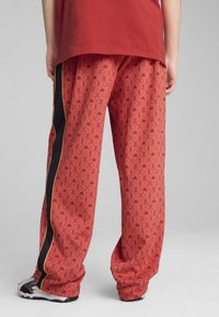 Røde mønstrede bukser med et geometrisk design, løst fit og sidelommer i sort med gul piping. Fremstillet af letvægtsstof.