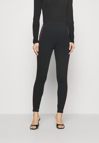 Zwarte leggings met een slim fit, voorzien van een contrasterende rode zijstreep, zacht materiaal en een elastische tailleband voor comfort.