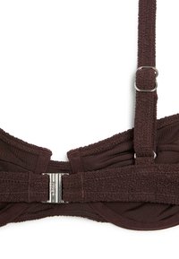 Dos de soutien-gorge texturé marron foncé avec bretelle réglable et fermeture à agrafe en métal argenté sur fond blanc.