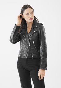 Giubbotto motociclistico in pelle nera con design accorciato, cerniere in argento, bottoni a pressione e ampi rever. Texture liscia con silhouette aderente.