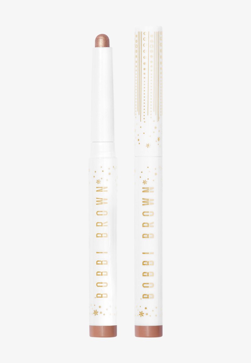 Metallic rose gold cream stick and cap with raised gold accents. White tube with a smooth finish and starry design. Features "Bobbi Brown" logo.