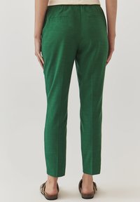 Groene broek met een gladde textuur, rechte snit en elastische tailleband. Beschikt over twee achterzakken en een subtiele glansafwerking.