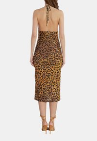 Abito leopardato marrone e oro con scollo all'americana, design senza schiena, silhouette aderente e lunghezza fino alle ginocchia, abbinato a scarpe con tacco alto.
