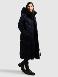 Marineblå pufferjakke med høj krave, der har lynlåslukning og sidelommer. Designet inkluderer trykknapdetaljer ved kanten.