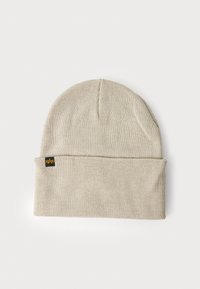 Gorro de malha em bege claro, com a bainha dobrada, textura com padrão e uma pequena etiqueta de logo preta de um lado.