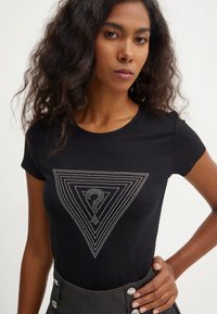 Zwarte T-shirt met korte mouwen, voorzien van een strassgrafiek van een driehoekpatroon met een centrale vraagtekenontwerpen.