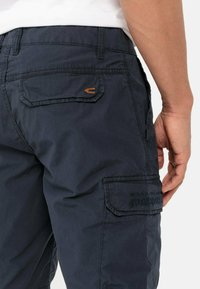 Marine cargobroek van een gestructureerde stof, met een achterzak met een klein geborduurd logo en een extra zijzak.