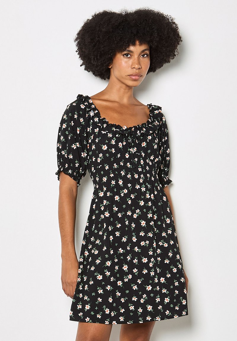 Vestito nero a fiori con maniche corte a sbuffo e scollo arricciato. Presenta piccoli fiori rosa e bianchi con foglie verdi su un tessuto strutturato.