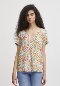 T-shirt à manches courtes et décolleté en V avec un motif ikat multicolore. Tissu léger avec une surface légèrement texturée et une coupe décontractée.