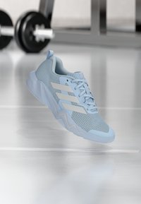 Zapatilla deportiva azul claro con parte superior de malla, detalles blancos y suela texturizada. Cuenta con un cuello acolchado y un diseño con cordones.