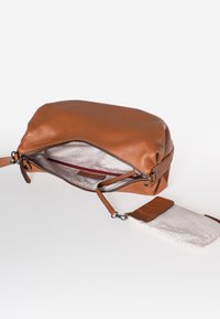 Bruine leren tas met een gestructureerd oppervlak, ritsluiting en een lichte binnenkant. Inclusief een kleine accessoire tas met een patroon aan de buitenkant.
