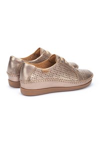 Zapatos de cuero perforado en bronce con suelas de goma beige, que presentan un diseño cosido y un cierre con cordones.