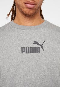 Szary sweter ze mieszanki bawełny, z okrągłym dekoltem i dużym czarnym logo PUMA na klatce piersiowej. Miękka faktura.