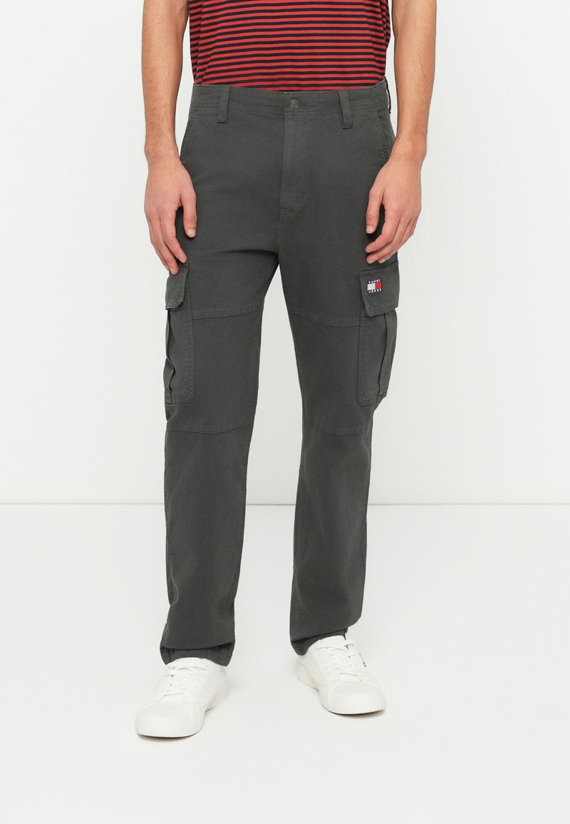 Mørkegrå cargo-bukser med flere lommer som fullfører en rett ben-design. Kombinert med hvite sneakers for kontrast.