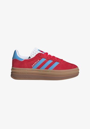 Baskets Adidas Gazelle rouges avec bandes bleu clair, languette bleue au talon, languette blanche, lacets rouges et semelle épaisse marron en couches.