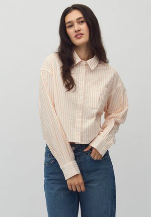 Cropped shirt with button closure, featuring light peach and white vertical stripes and a single chest pocket. Soft fabric with long sleeves.