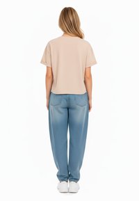 Top beige a maniche corte con vestibilità rilassata, abbinato a jeans baggy blu chiaro con orlo risvoltato e tasche posteriori.