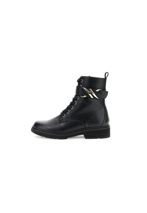 Black leather ankle boot featuring a rounded toe, lace-up front, and a decorative gold metal accent on the upper strap. Flat sole.