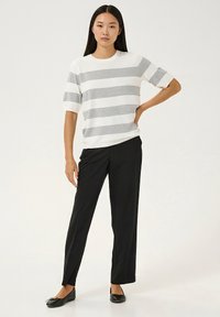 Bela in sivo črtasta majica s kratkimi rokavi, kombinirana s črnimi hlačami z ravnimi hlačnicami in ravnimi čevlji; gladek material z bolj sproščenim krojem.