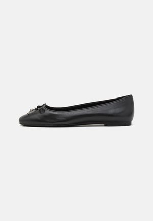 Ballerine plate en cuir noir avec bout arrondi, petit nœud et breloque argentée sur fond blanc.
