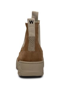 Botín de ante marrón con paneles laterales crema y acentos texturizados. Presenta una pestaña de tirón y una suela de goma beige con un patrón texturizado.