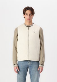 Švarkelis šviesiai beige spalvos, su užtrauktuku ir dviem šoniniais kišenėmis, su mažo siuvinėto logotipo ant krūtinės, derinamas su ilgomis rankovėmis.