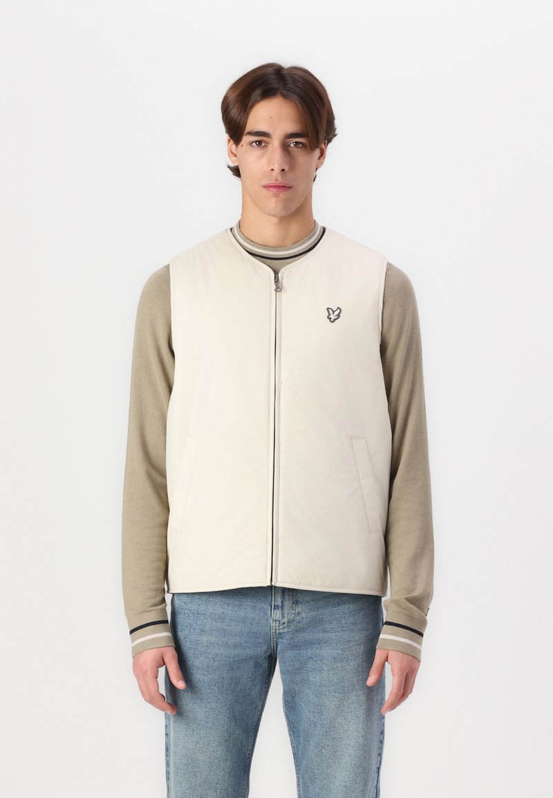 Švarkelis šviesiai beige spalvos, su užtrauktuku ir dviem šoniniais kišenėmis, su mažo siuvinėto logotipo ant krūtinės, derinamas su ilgomis rankovėmis.