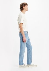 Short-sleeve cream t-shirt, light blue jeans, and white sneakers. Straight fit with a smooth texture, minimal detailing, and a classic design.