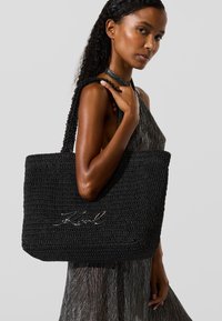 Fekete, szőtt bevásárlótáska texturált horgolt designnal és a jól ismert "Karl" logó ezüst színben az elején, fonott pántokkal.