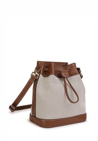 Bucket bag with a light beige body and brown leather accents, featuring a drawstring closure and a removable shoulder strap.