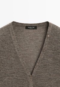 Hnědý svetr s výstřihem do V z měkké pletené látky, s texturovaným povrchem a třemi knoflíky na přední straně. Viditelná značka.