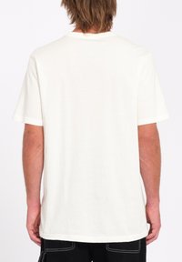 Camiseta de algodón de crema claro con un corte relajado, mangas cortas y cuello redondo; textura suave y sin patrones o diseños visibles.