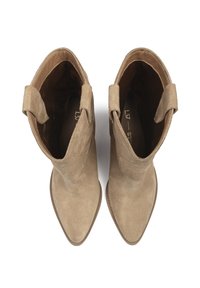 Pár béžových semišových kotníkových bot s špičatými špičkami a poutky na tahání, pohled shora na bílém pozadí.