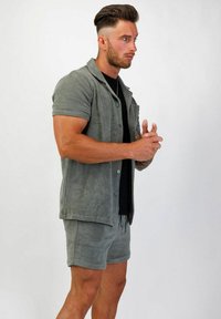 Ljusgrå frottéklänning och matchande shorts. Kortärmad skjorta med knäppning fram; shorts med elastisk midja och avslappnad passform.