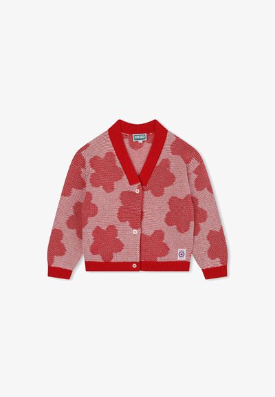 Cardigan en tricot rouge avec un motif de fleurs rouges et blanches, col châle, fermeture par boutons, et poignets et ourlet côtelés. Étiquette visible en bas à droite.