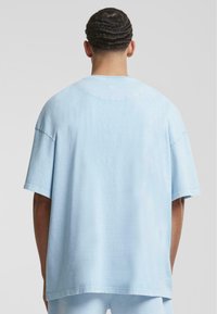T-shirt oversize bleu clair en coton, avec un col rond, des manches courtes et une finition de tissu lisse et non texturé.