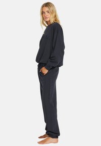Mørkeblå sweatshirt og bukser i blødt stof. Rund hals, afslappet pasform med sidelommer. Branding præget på bukserne.