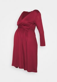 Gravidklänning i djup vinröd färg med långa ärmar, V-ringning, omlottstil och en rynkad detalj vid midjan för komfort.