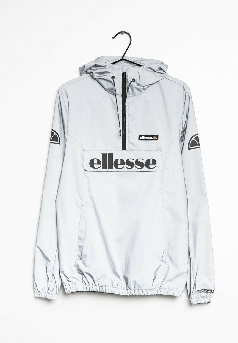 Ljust grå Ellesse huva vindjacka med halv-zip, framficka med klaff, elastiska ärmslut och svarta logotryck på bröstet och ärmarna.