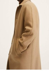 Beige Wollmantel mit geradem Schnitt, großem Kragen und seitlichen Taschen. Hat eine glatte Textur und Knopfdetails entlang der Vorderseite.