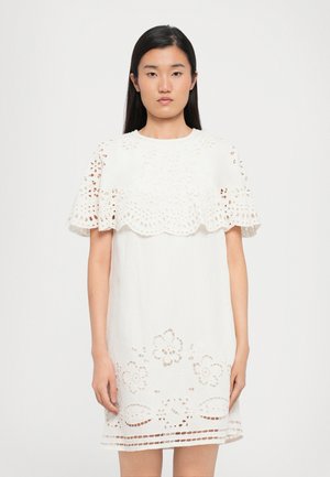 Witte jurk met gelaagd, gekarteld kant overlay en bloemen uitsneden aan de zoom. Korte mouwen en een rechte silhouet.