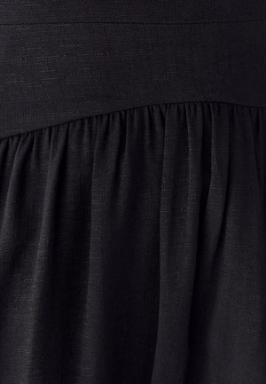 Vestido negro con tela texturizada, que presenta un cuerpo ajustado y una falda con fruncidos. El material parece ligero y suave.