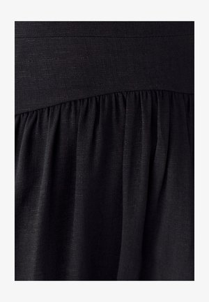 Schwarzes Kleid aus strukturiertem Stoff, mit einem taillierten Oberteil und gerafftem Rock. Das Material wirkt leicht und glatt.